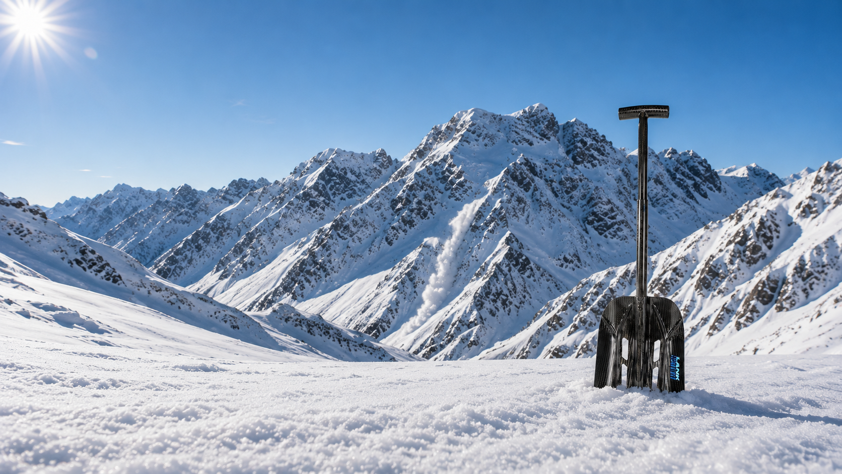 LANK carbon avalanche shovel standing upright in snow on an alpine ridge with sunburst